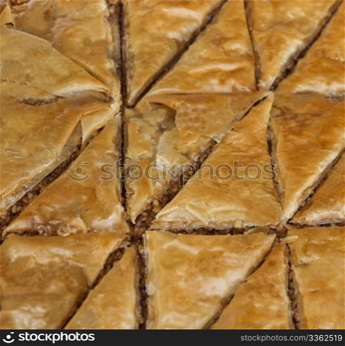 Triangular shapes of Baklava, a pastry made of ingredients including phyllo leaves, nuts, and honey.