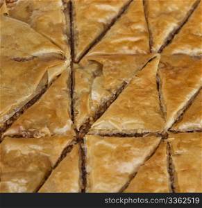 Triangular shapes of Baklava, a pastry made of ingredients including phyllo leaves, nuts, and honey.