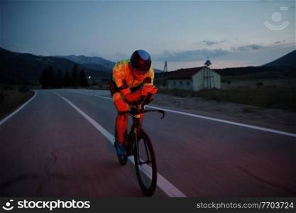 triathlon athlete riding professional racing bike at night workout on curvy country road w
