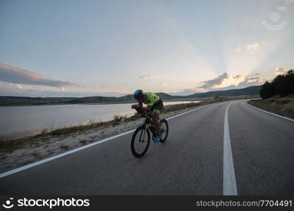 triathlon athlete riding professional racing bike at workout on curvy country road