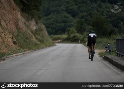 triathlon athlete riding racing bike on morning training wearing black sporty clothes