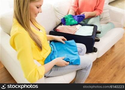 trip, vacation, luggage and people concept - close up of happy young woman or teenage girl packing clothes into travel bag