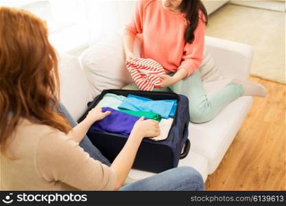trip, vacation, luggage and people concept - close up of young woman or teenage girl packing clothes into travel bag