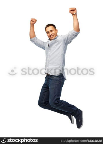 triumph, power and people concept - happy young man jumping over white background. happy young man jumping over white background