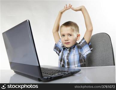 Triumphing child boy with a laptop notebook computer on white background. Computer addiction.