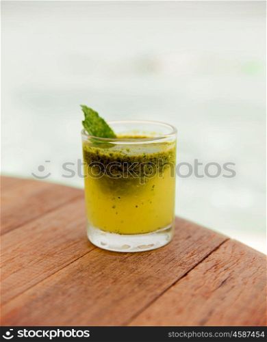 trivet, tourism, drinks and food concept - glass of fresh juice or cocktail on table at beach