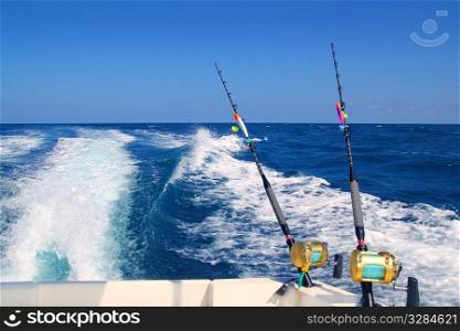 Trolling fishing boat rod and golden saltwater reels deep blue ocean sea wake