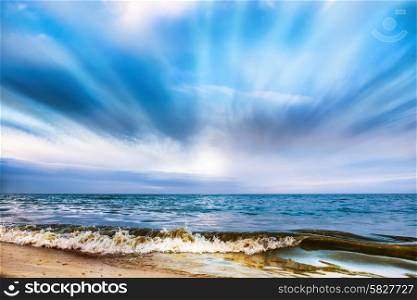 Tropical beach and blue sea with waves, white clouds on background