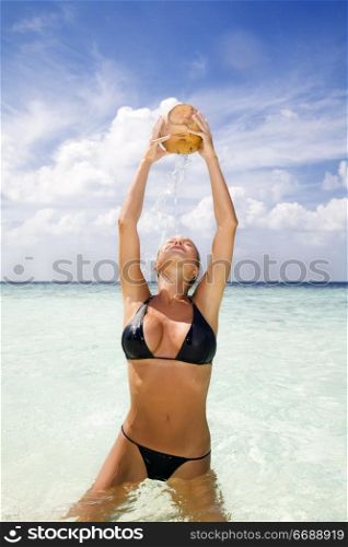 tropical beach: beautiful girl drinking from a coconut in her hands