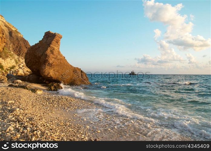 Tropical beach on the sunset with water and rocks.