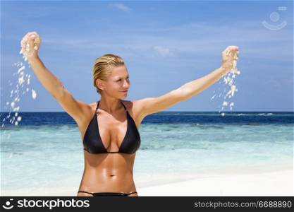 tropical beach: perfect girl playing with sand on a tropical beach