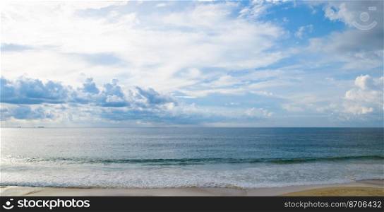 Tropical beach with high waves . Yellow warm sand and summer sea with sky and free space. Wide photo.