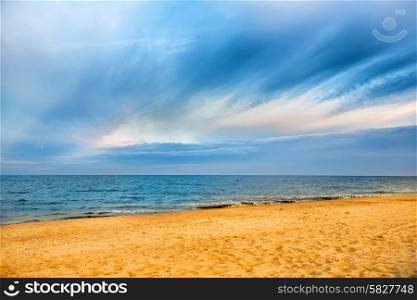 Tropical beach with yellow sand and blue sea with waves, white clouds on background