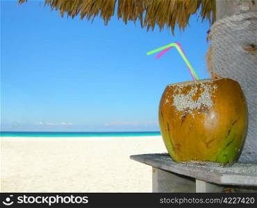 tropical coconut cocktail under beach umbrella on a sandy beach