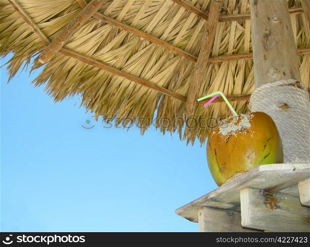 tropical coconut cocktail under beach umbrella on a sandy beach