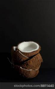 Tropical fruit concept, Fresh coconut halves stacked on a black background.