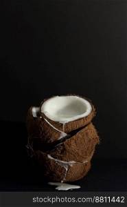 Tropical fruit concept, Fresh coconut halves with coconut milk stacked on a black background.