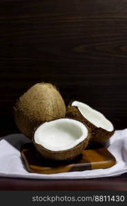 Tropical fruit concept, Halves of fresh coconuts and coconut on wooden saucer with white fabric.