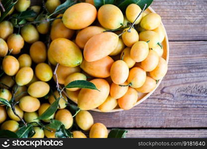 tropical fruit Name in Thailand Sweet Yellow Marian Plum Maprang Plango or Mayong chid, Marian plum fruit and leaves in plate on wooden background