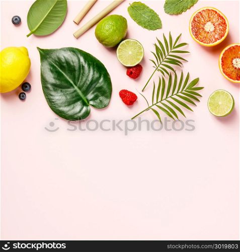 Tropical fruits and leaves on pink pastel background. Top view, flat lay, space for text. Tropical fruits and leaves on pink pastel background