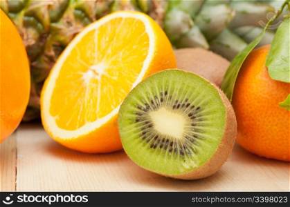 Tropical Fruits - Pineapple, Oranges, Tangerine and Kiwi on Wooden Table