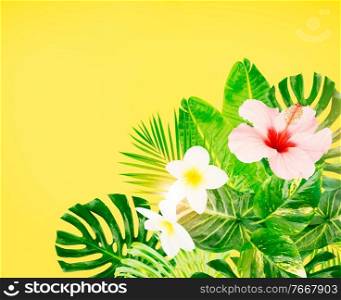 Tropical green leaves and flowers frame on yellow background with copy space toned image. Tropical green leaves