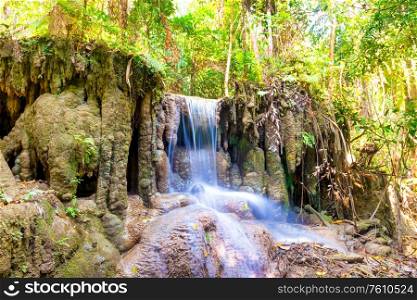 Tropical landscape with beautiful waterfall and rocks in wild green jungle forest. Erawan National park, Kanchanaburi, Thailand