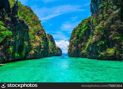 Tropical landscape with rock islands, lonely boat and crystal clear water, El Nido, Palawan, Philippines