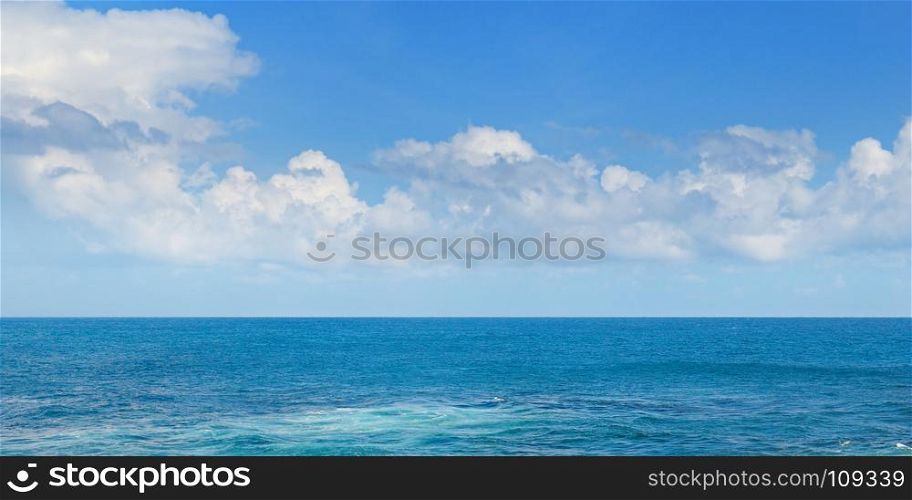 Tropical ocean, beach, high waves and blue sky. Wide photo.