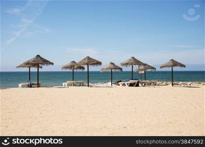 tropical parasols on the algarve beach with the sea as background