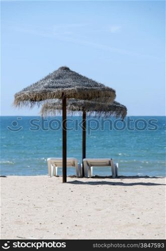 tropical parasols on the algarve beach with the sea as background