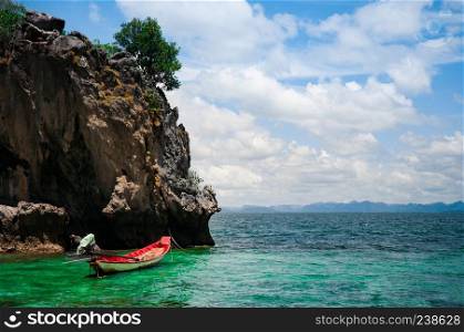 Tropical rock island and a fishing boat.