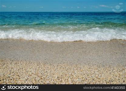 Tropical sand beach with sea waves and stones.