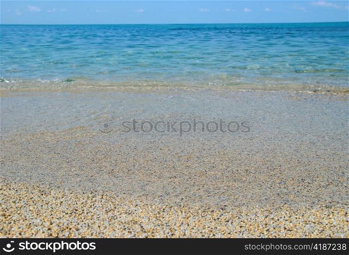 Tropical sand beach with sea waves and stones.