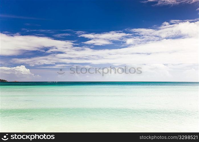 Tropical seascape: the horizon over an turquoise sea, blue sky and white clouds