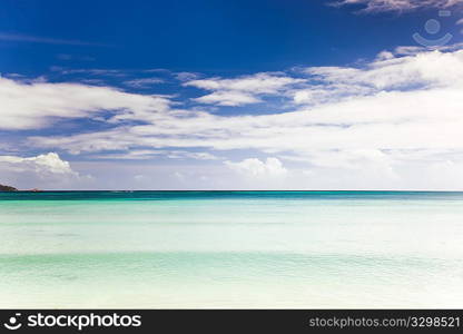 Tropical seascape: the horizon over an turquoise sea, blue sky and white clouds