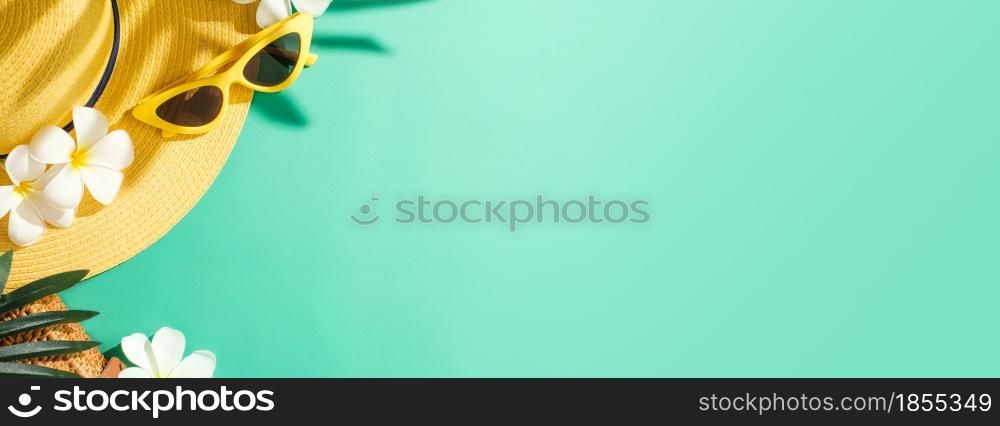 Tropical summer beach sea accessories objects,sunglasses,yellow hat and white flower over green turquoise background banner with sunlight