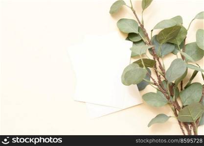 Tropical summer stationery mock-up scene. Blank business card, green eucaliptus leaves, beige textured table background. Flat lay, top view. summer stationery mock-up scene.