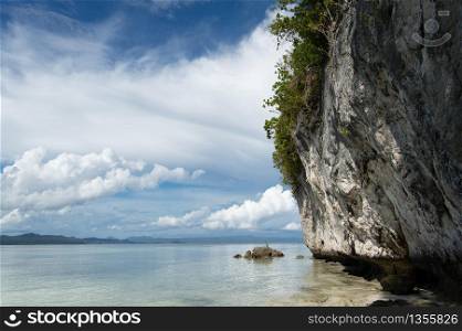 Tropical white limestone cliff over the calm sea in Kri island, Raja Ampat, Indonesia