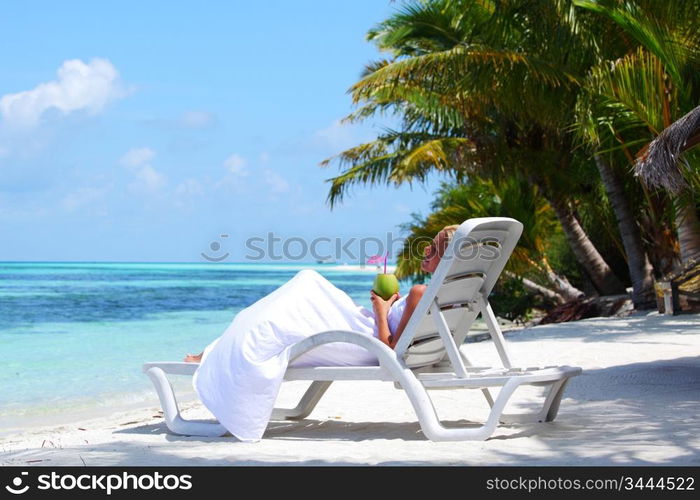 tropical woman on lounge with a coconut cocktail