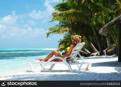 tropical woman on lounge with a coconut cocktail