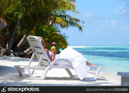 tropical woman on lounge with a coconut cocktail