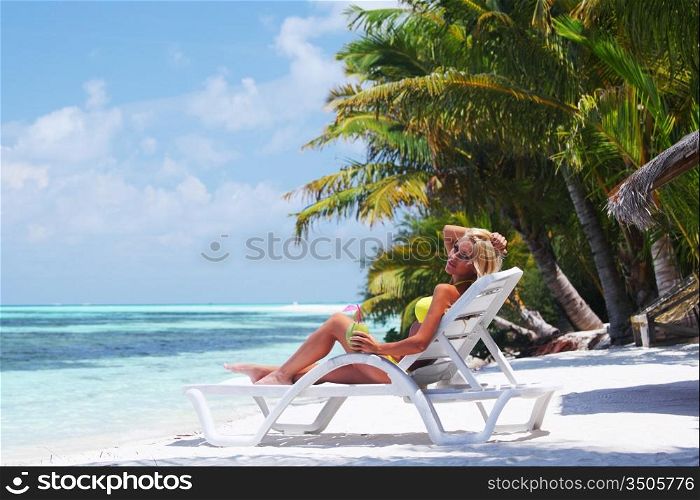 tropical woman on lounge with a coconut cocktail