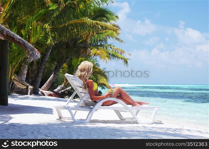tropical woman on lounge with a coconut cocktail