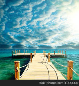 tropical wooden pier in turquoise sea at sunny weather, clear skies