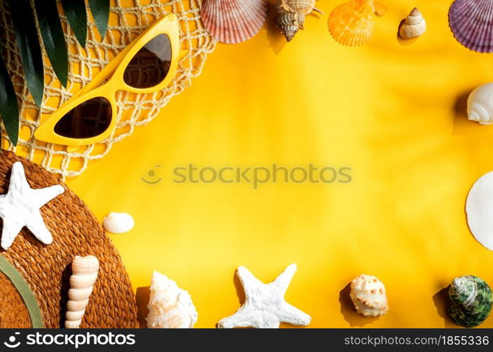 Tropical yellow summer beach sea accessories objects,sunglasses,brown hat and seashell over yellow background banner with sunlight