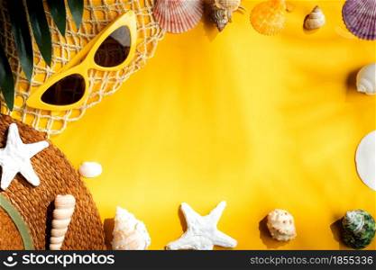 Tropical yellow summer beach sea accessories objects,sunglasses,brown hat and seashell over yellow background banner with sunlight