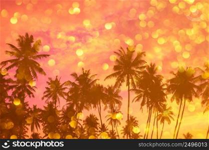 Tropiocal beach at sunset with palm trees silhouettes and golden shiny bokeh double exposure effect