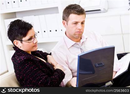 Troubled businessman and female assistant working on a laptop computer at office.