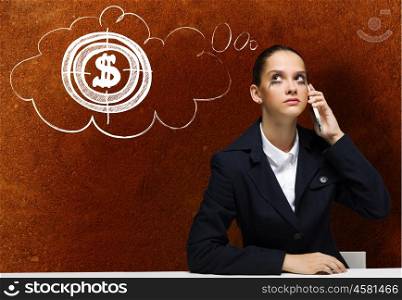 Troubled businesswoman. Young upset businesswoman sitting at table and talking on mobile phone
